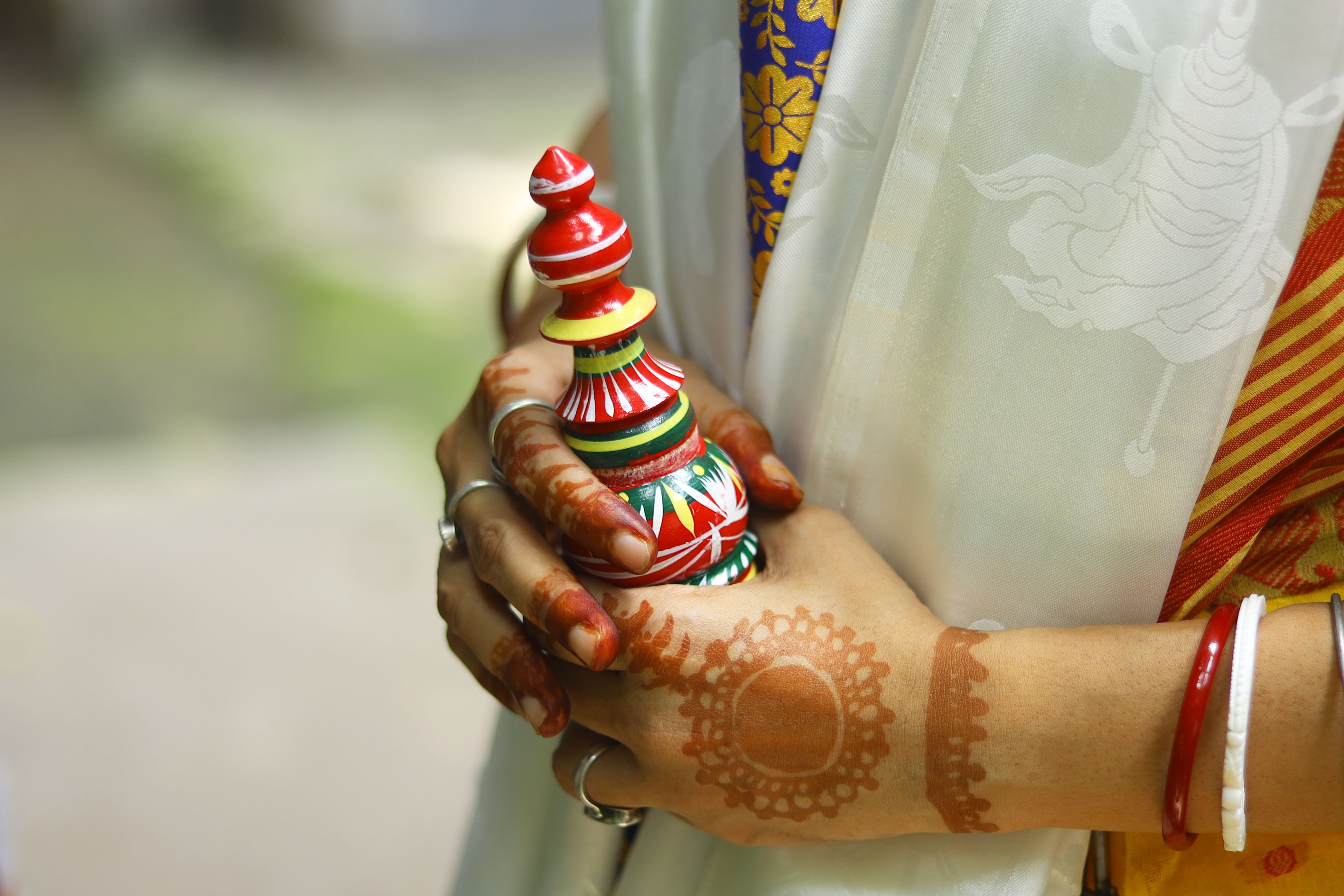 Detailed view of a woman's hennaed hands holding traditional Indian handcraft in Kolkata.