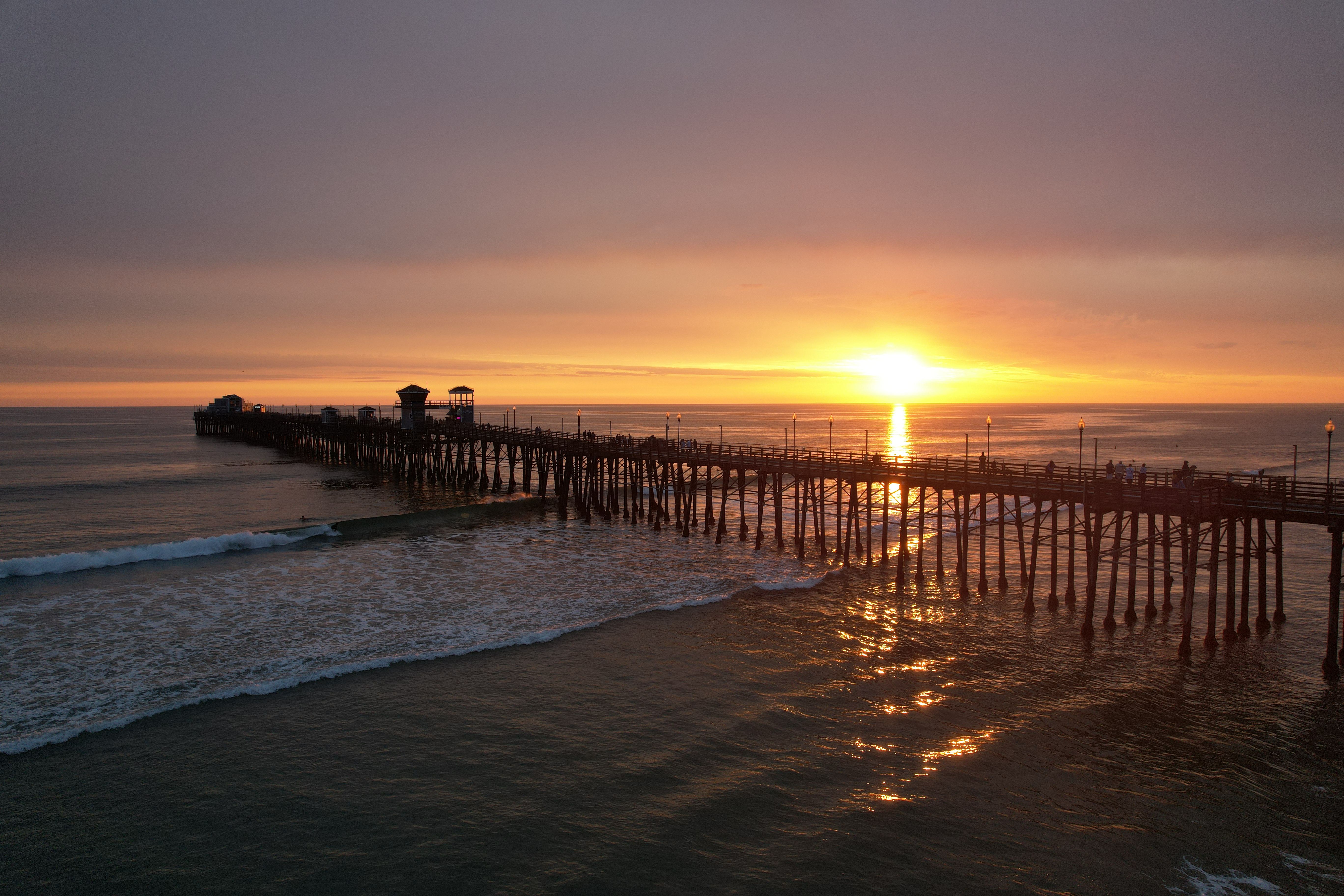Breathtaking view of Oceanside Pier during a vibrant sunset with waves crashing gently on the shore.