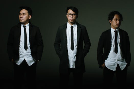 Portrait of three Asian men in suits, standing against a gray background.