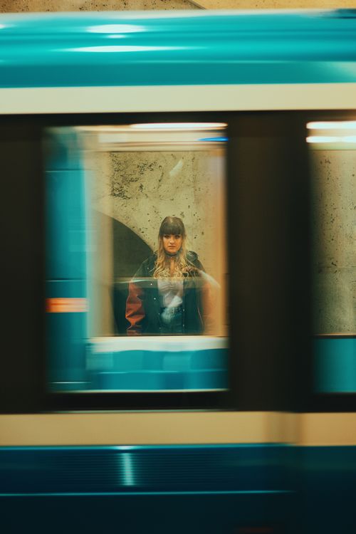 Free A woman stands visible through a moving subway train window in an urban metro setting. Stock Photo