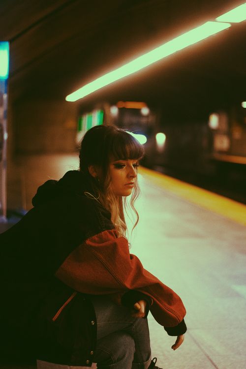 Free Pensive woman sitting on a dimly lit metro platform, conveying an urban and reflective mood. Stock Photo