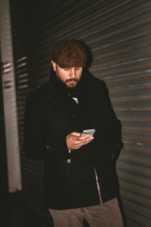 Man in Black Coat Standing with Smartphone