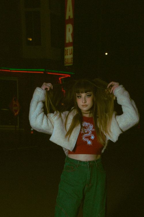 Free Fashionable woman adjusting hair in urban nighttime setting. Stock Photo