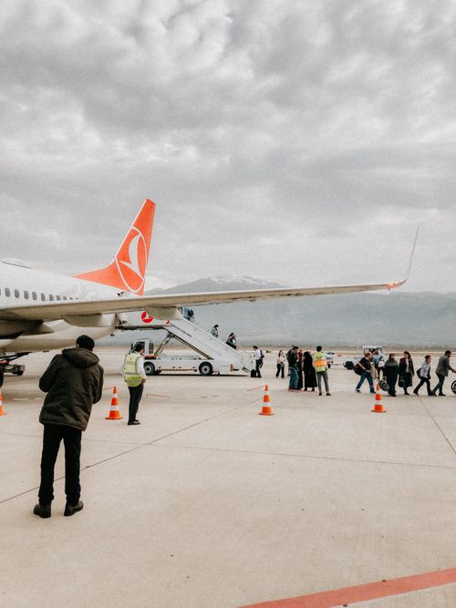 Free Passengers disembarking a Turkish Airlines jet on the tarmac with mountains in the background. Stock Photo
