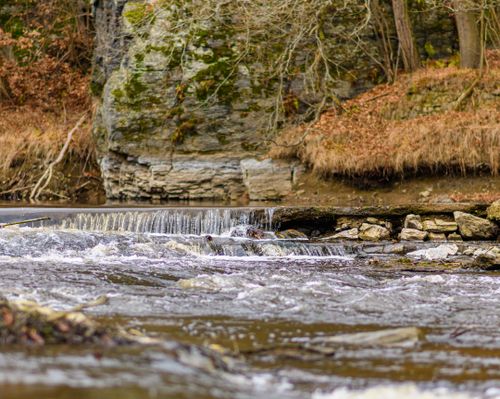 Free Tranquil waterfall cascading over rocks in an autumn forest setting, showcasing nature's changing seasons. Stock Photo