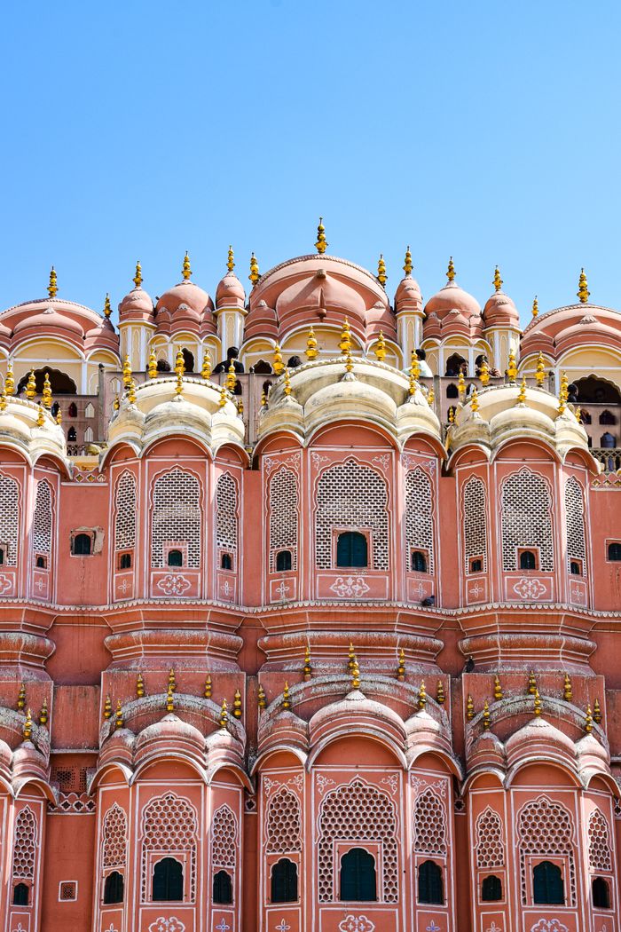 Ornate pink sandstone facade of Hawa Mahal in Jaipur against a blue sky