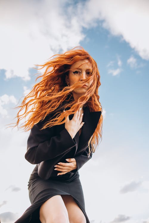 A woman with red hair and long red hair is standing on a cliff