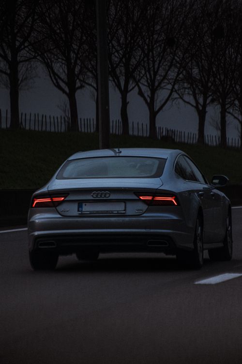 Free Back view of an Audi A7 car driving on a city street in Belgium during dusk. Stock Photo