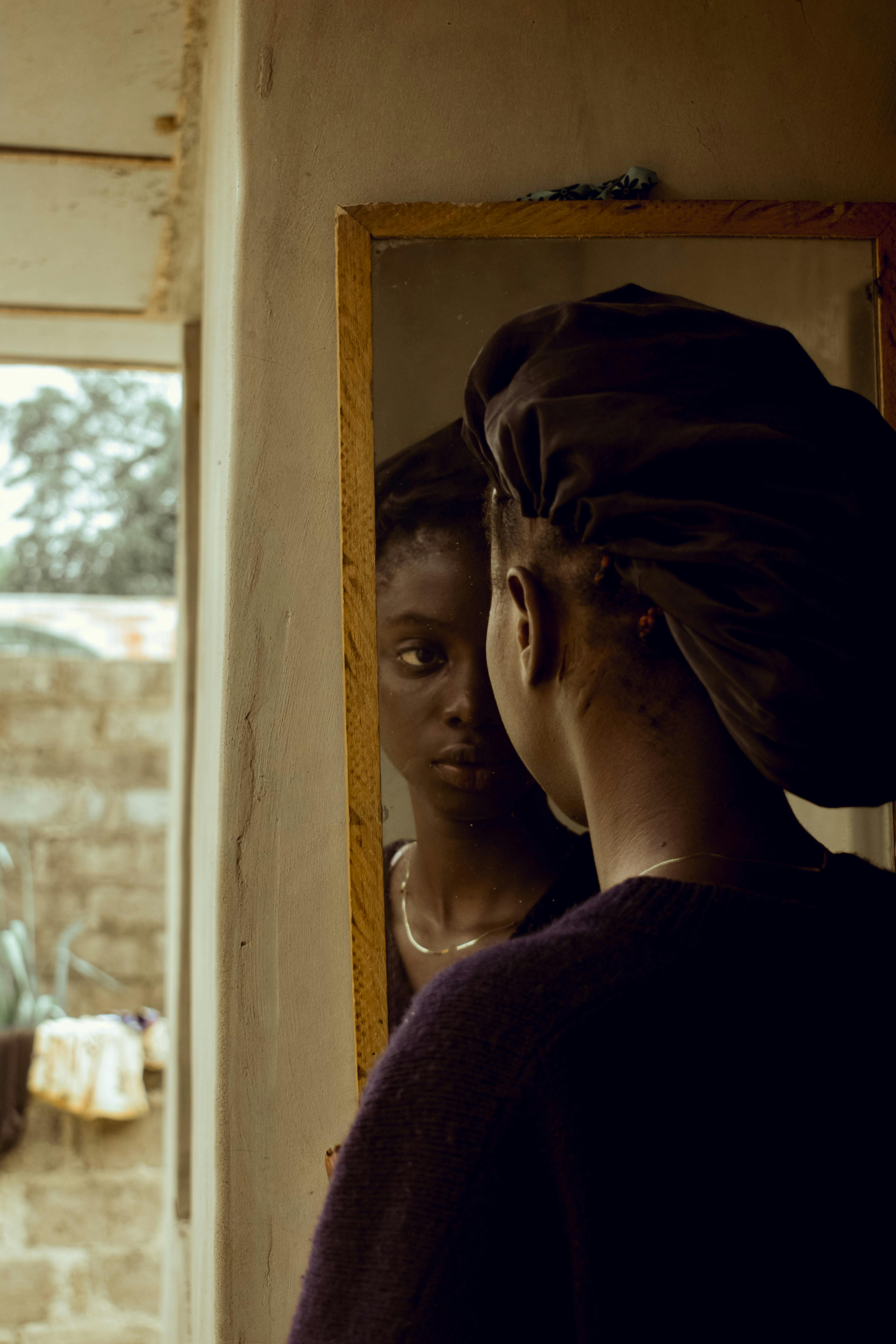 Woman in a black beret reflects in a vintage mirror indoors.