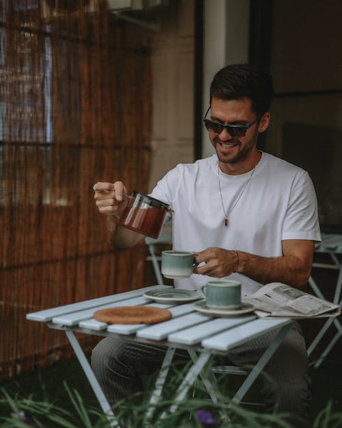 Smiling Man in Sunglasses Pouring Tea