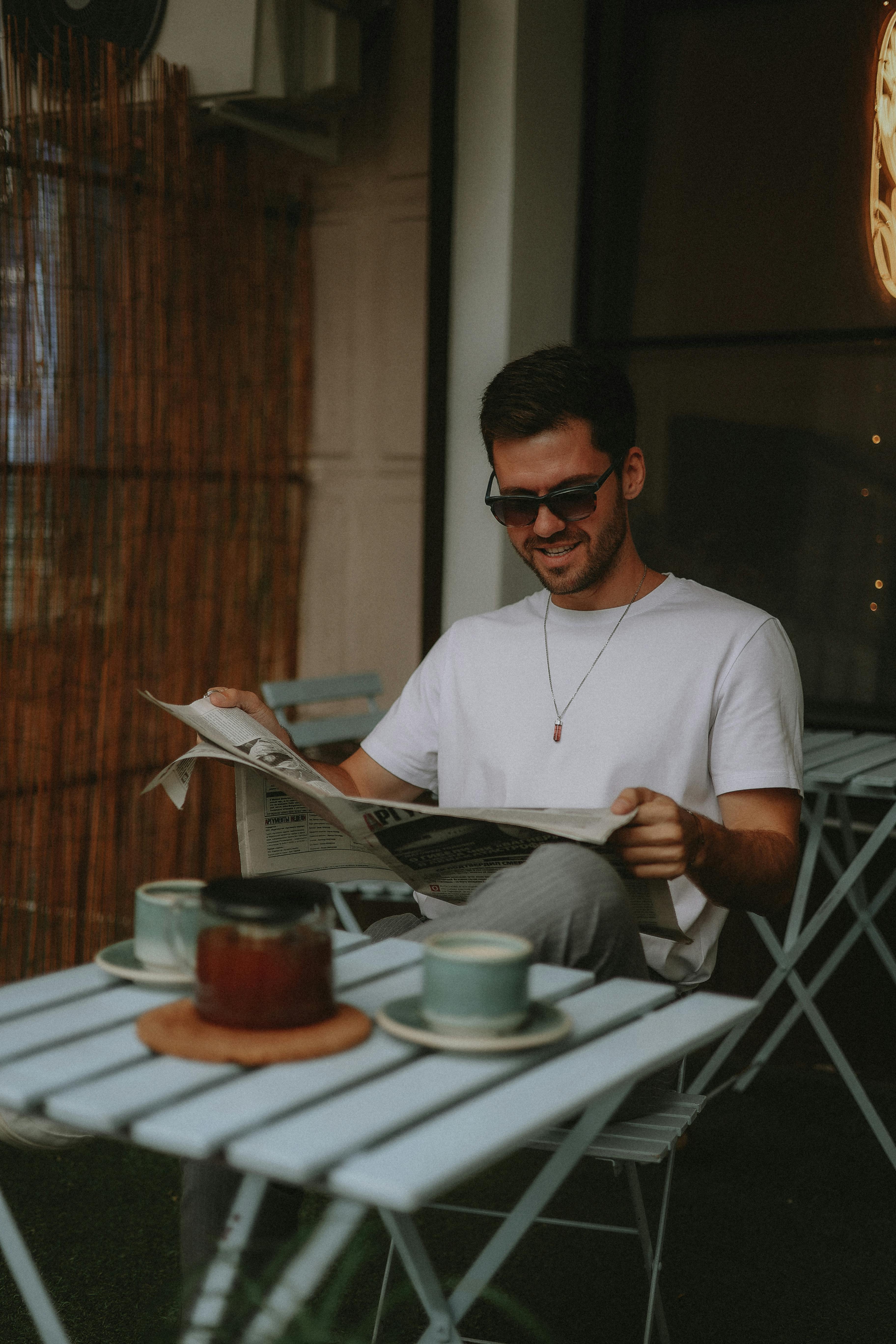 Premium Photo | Young woman wearing sunglasses reading newspaper at outdoor  cafe