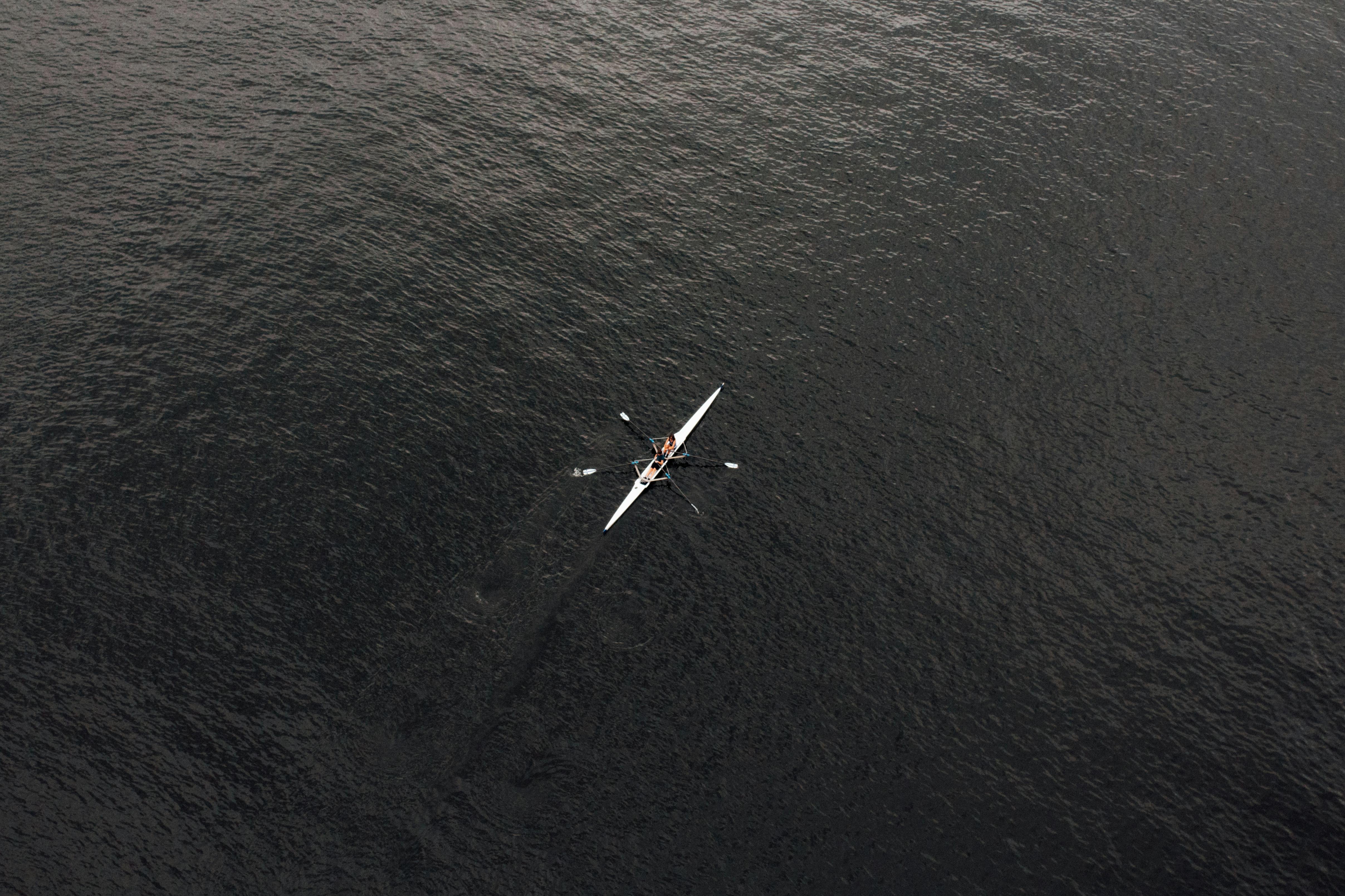 Aerial shot of a canoe with people paddling on the waters of Porto, Portugal.