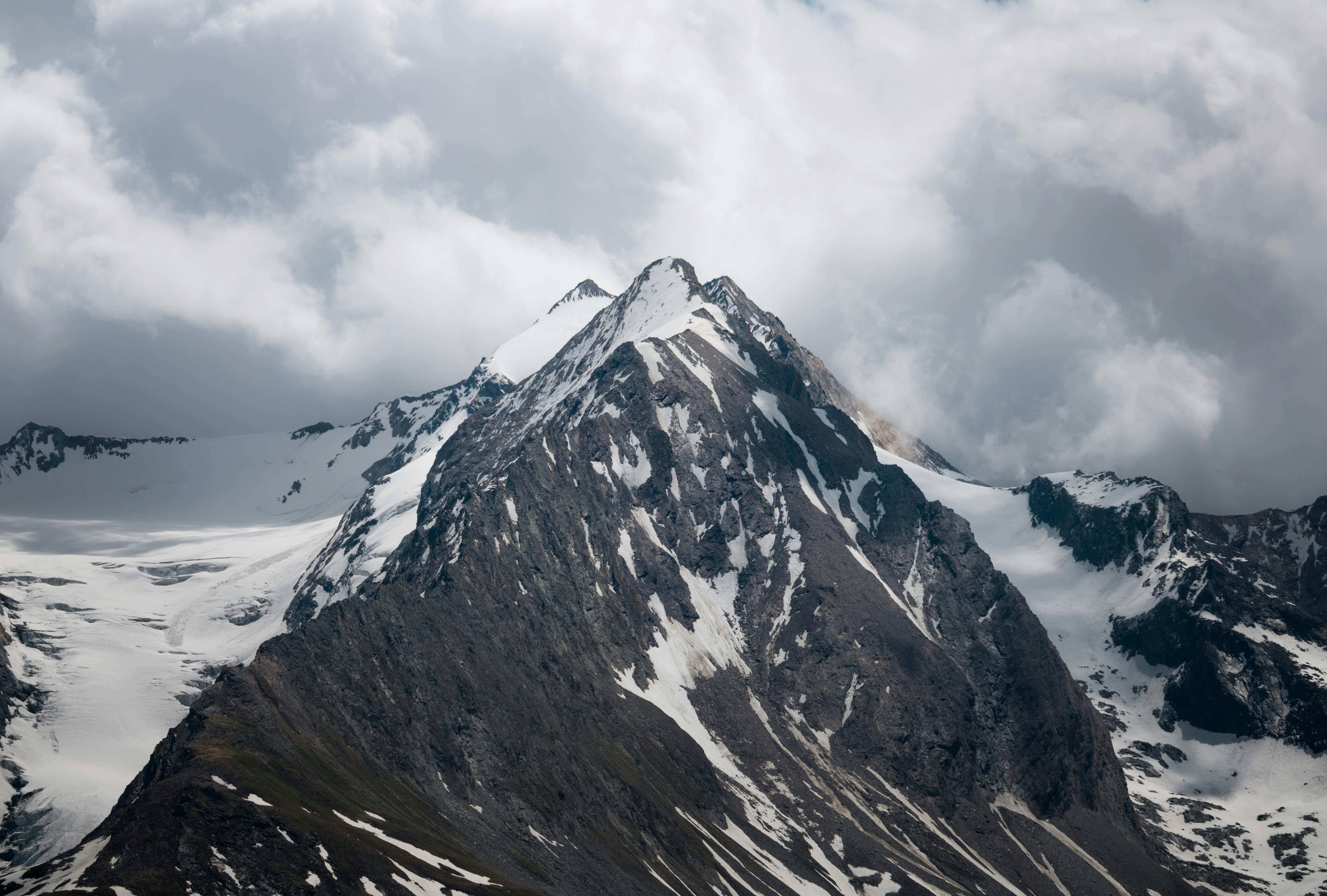 a mountain with snow on it under a cloudy sky