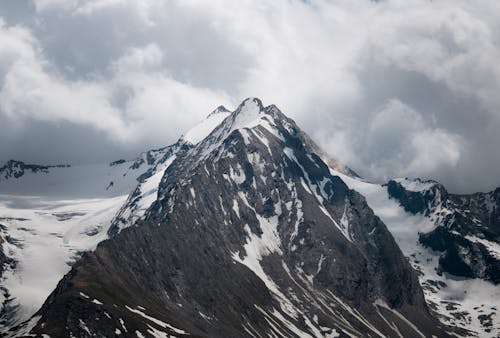 A mountain with snow on it under a cloudy sky