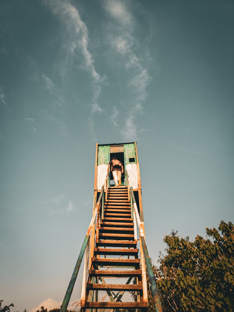 Person Walking Upstairs On Rusty Stairs Of Tower