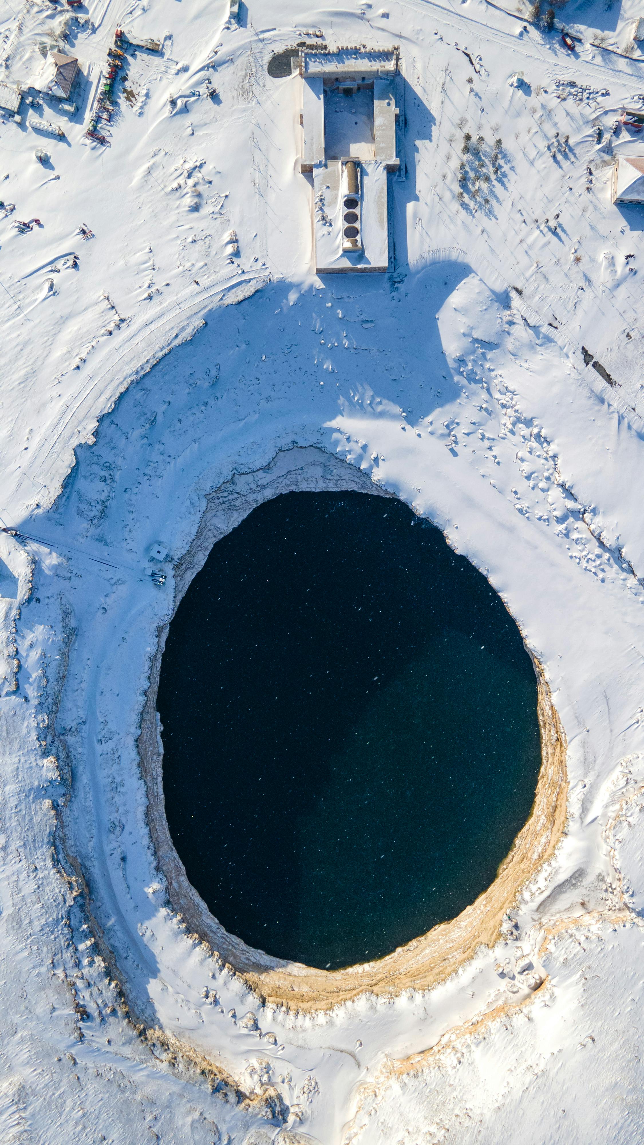Explore the stunning aerial view of the Kizoren sinkhole in winter, covered in snow.