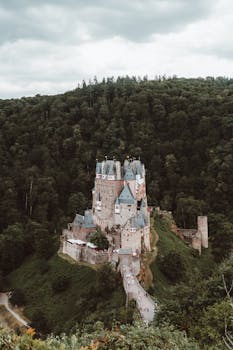 A breathtaking aerial shot of the medieval Eltz Castle surrounded by lush forests in Germany.