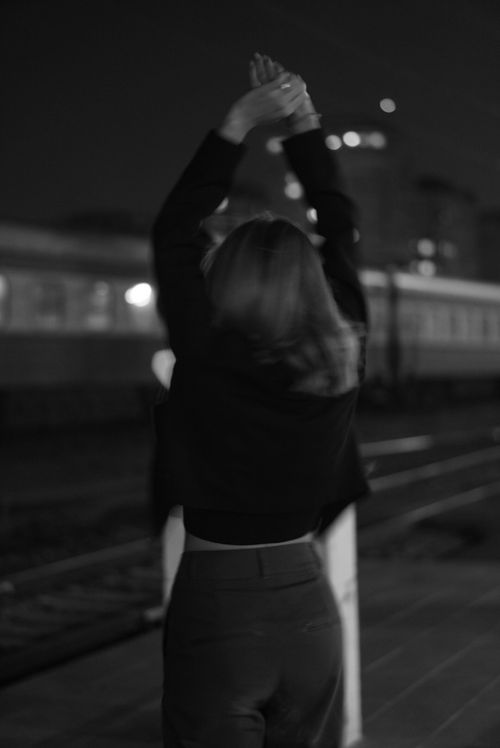 Free Back view of a woman raising arms in black and white at a train station. Stock Photo