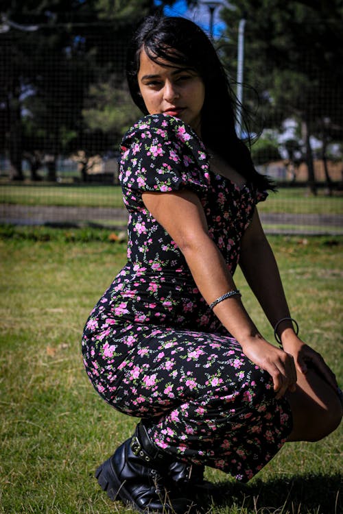 Young Woman in a Dress with a Floral Pattern Crouching Outside 