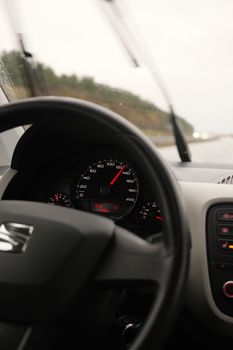 Car interior showing dashboard view with speedometer and steering wheel.
