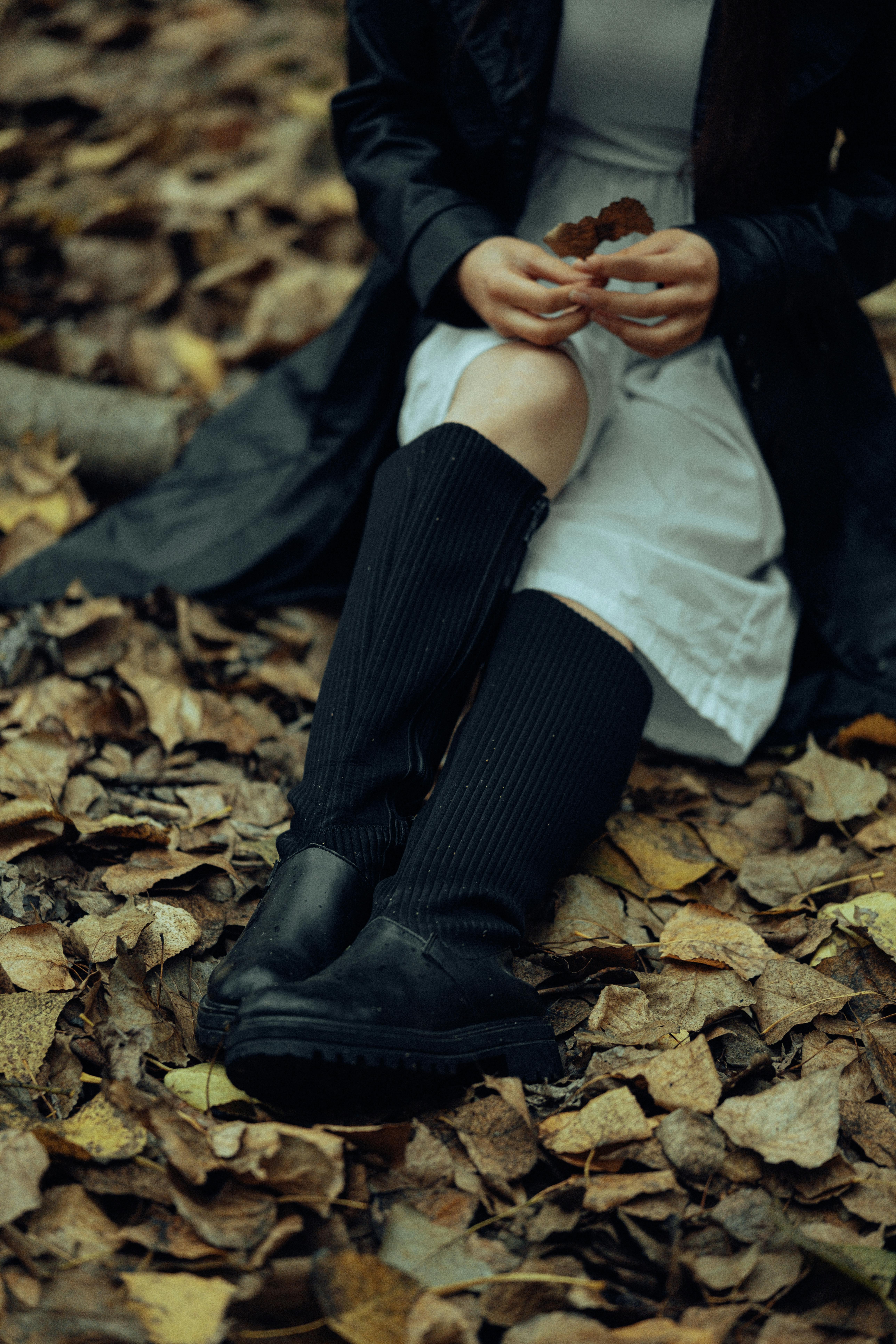 Close-up of legs in black boots amidst autumn leaves in Fethiye, Türkiye.