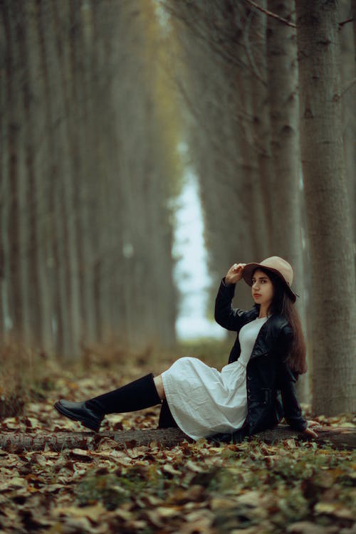 Young Woman Sitting on the Ground in a Park in Autumn