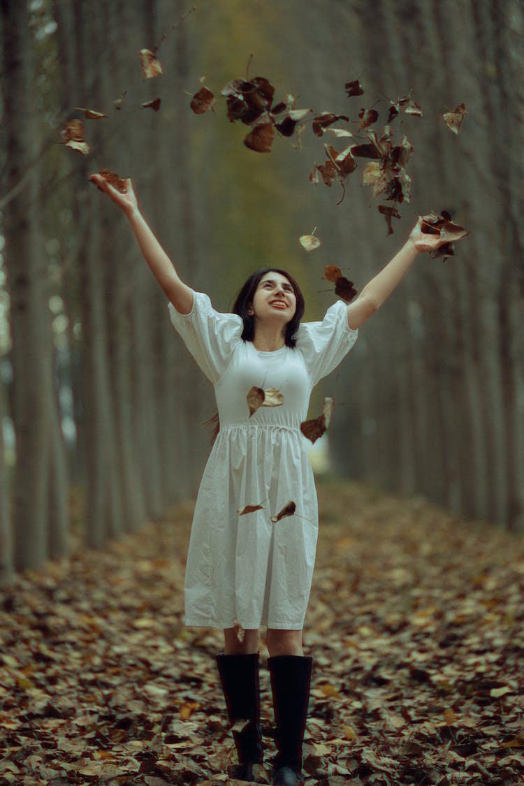 Smiling Woman Throwing Up Autumn Leaves