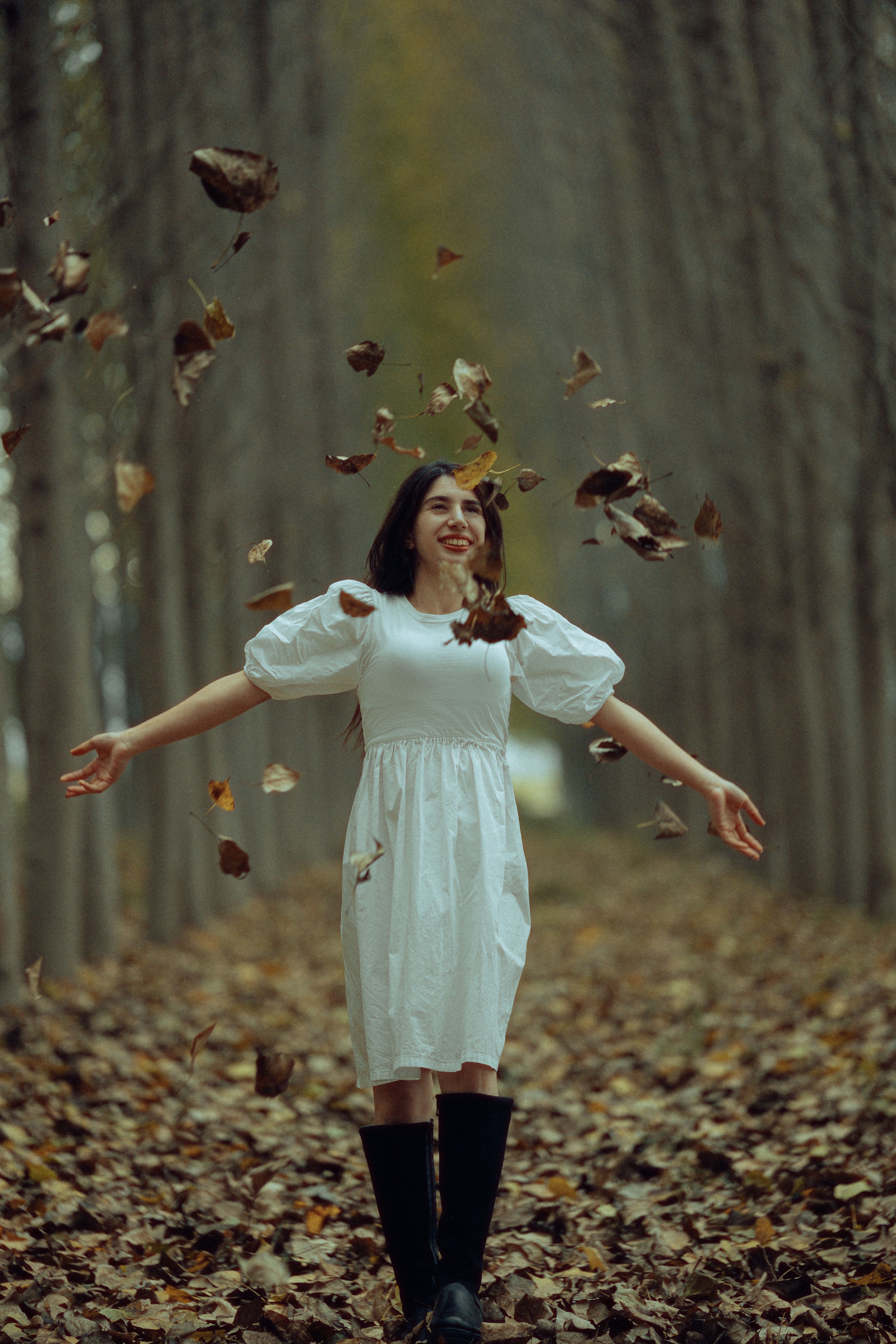 Leaves Flying around Smiling Woman in White Dress  Free Stock Photo