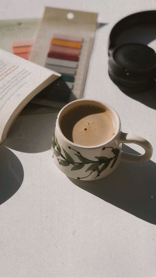 Free A cup of coffee on a table with a book, headphones, and color swatches. Stock Photo