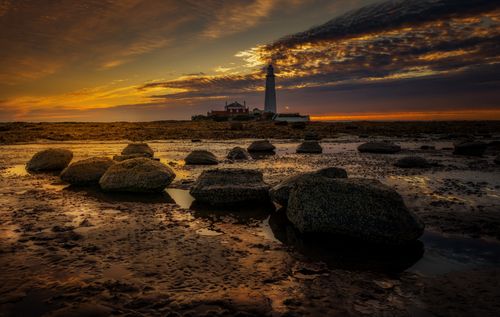 Free A breathtaking sunset at St Mary's Lighthouse, capturing the serene coastal beauty and dramatic sky. Stock Photo