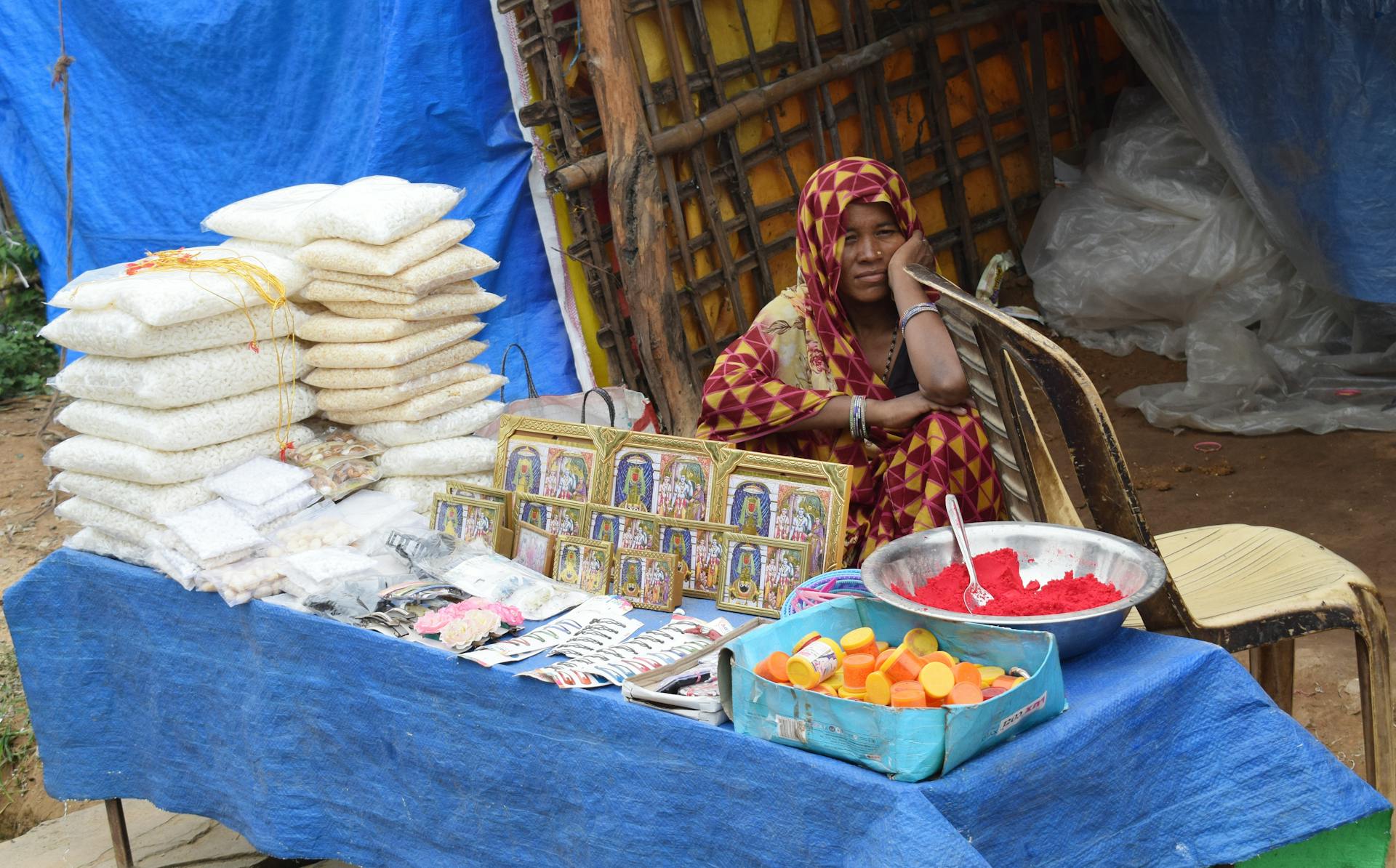 A local woman sits beside her street market stall selling traditional handcrafted goods and spices.