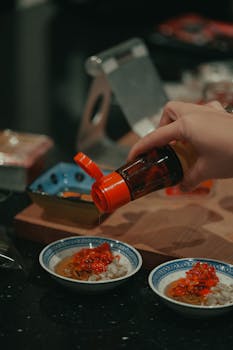 A person preparing authentic Chinese cuisine with chili sauce, showcasing culinary culture.