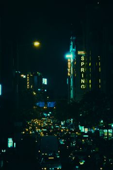Lively city street at night with bustling traffic and illuminated signs.