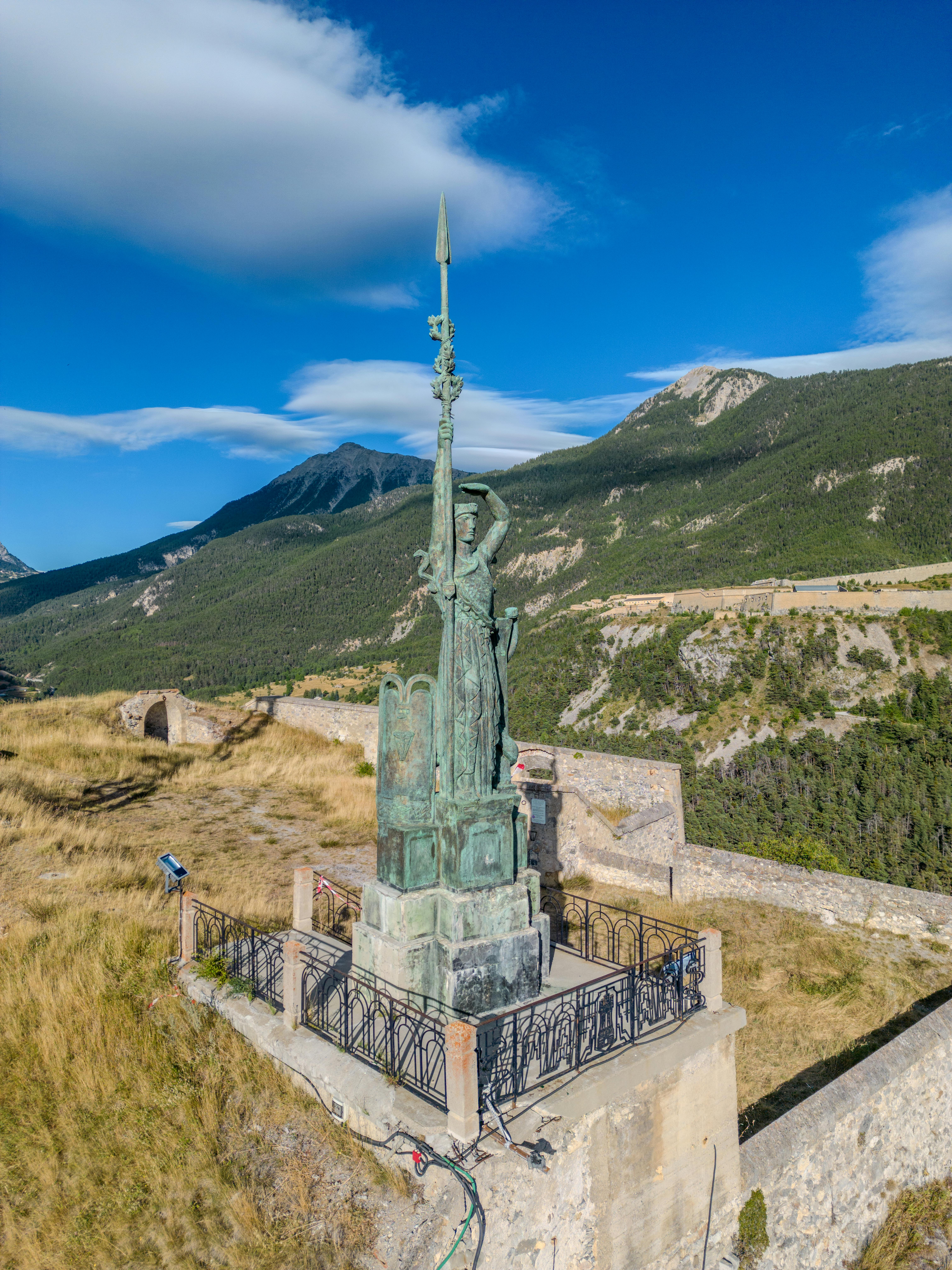 Drone shot of a historic statue in scenic Briançon, France's picturesque countryside.