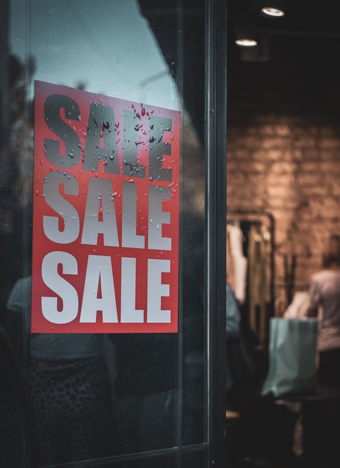 Shop window with a red Sale poster behind the glass