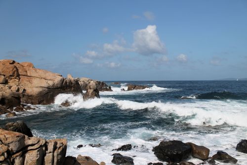 Free Dynamic view of crashing waves against rugged rocky shore under a clear blue sky. Stock Photo