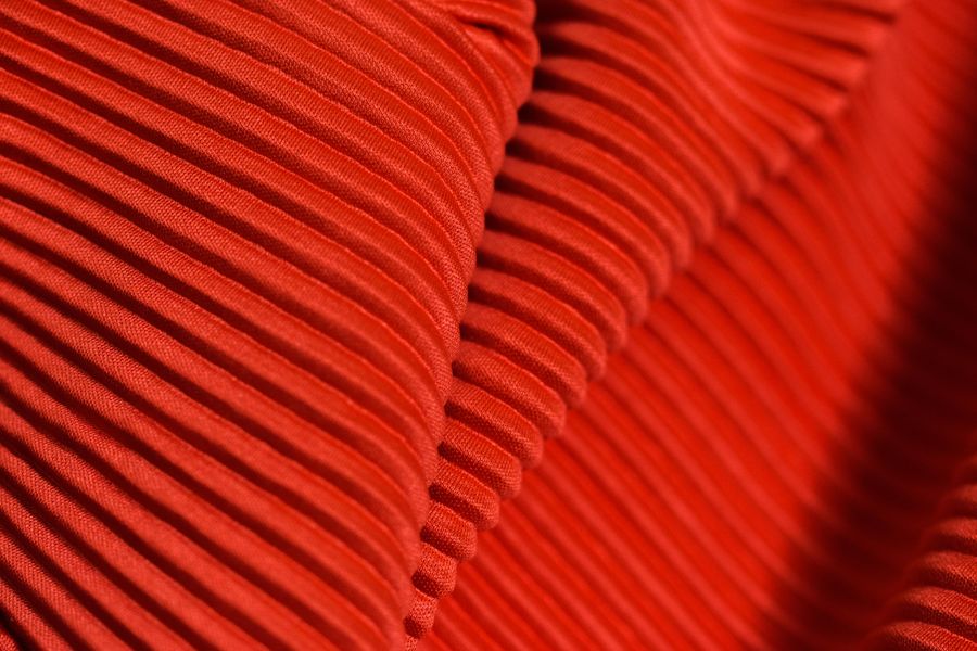 Closeup of red ribbed corduroy fabric showcasing its unique texture and pattern.