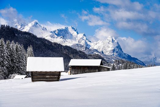 Peaceful winter landscape with snow-covered cabins and majestic mountains.