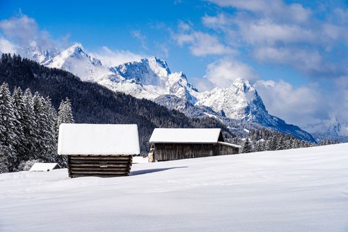 Free Peaceful winter landscape with snow-covered cabins and majestic mountains. Stock Photo