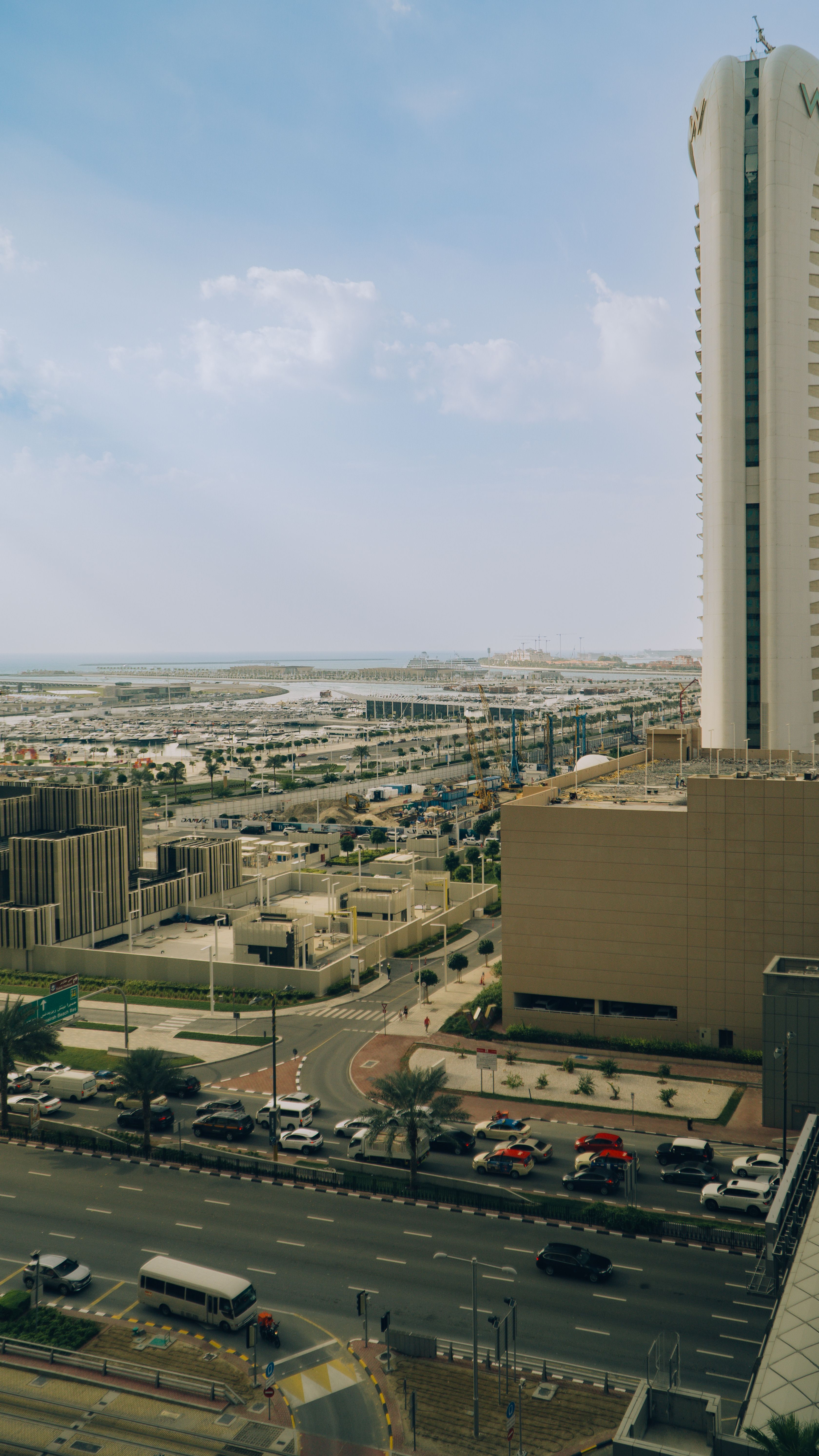 Vertical aerial view of Dubai's cityscape featuring a skyscraper and urban layout under a clear sky.