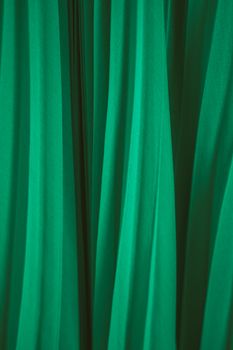 A close-up view of vibrant green fabric with flowing drapes, creating an elegant texture.