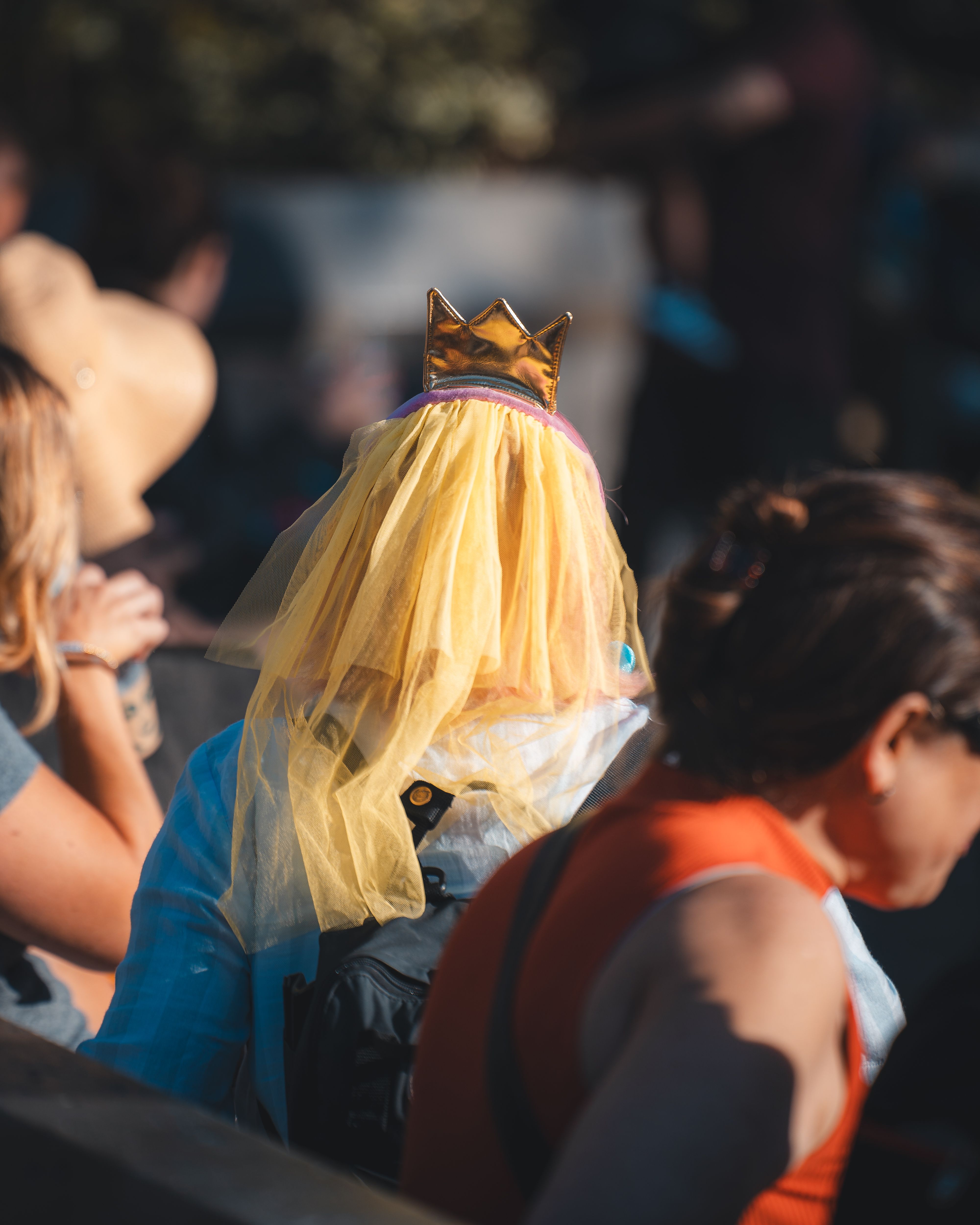A captivating rear view of a person wearing a colorful costume with a crown and yellow veil in an urban setting.