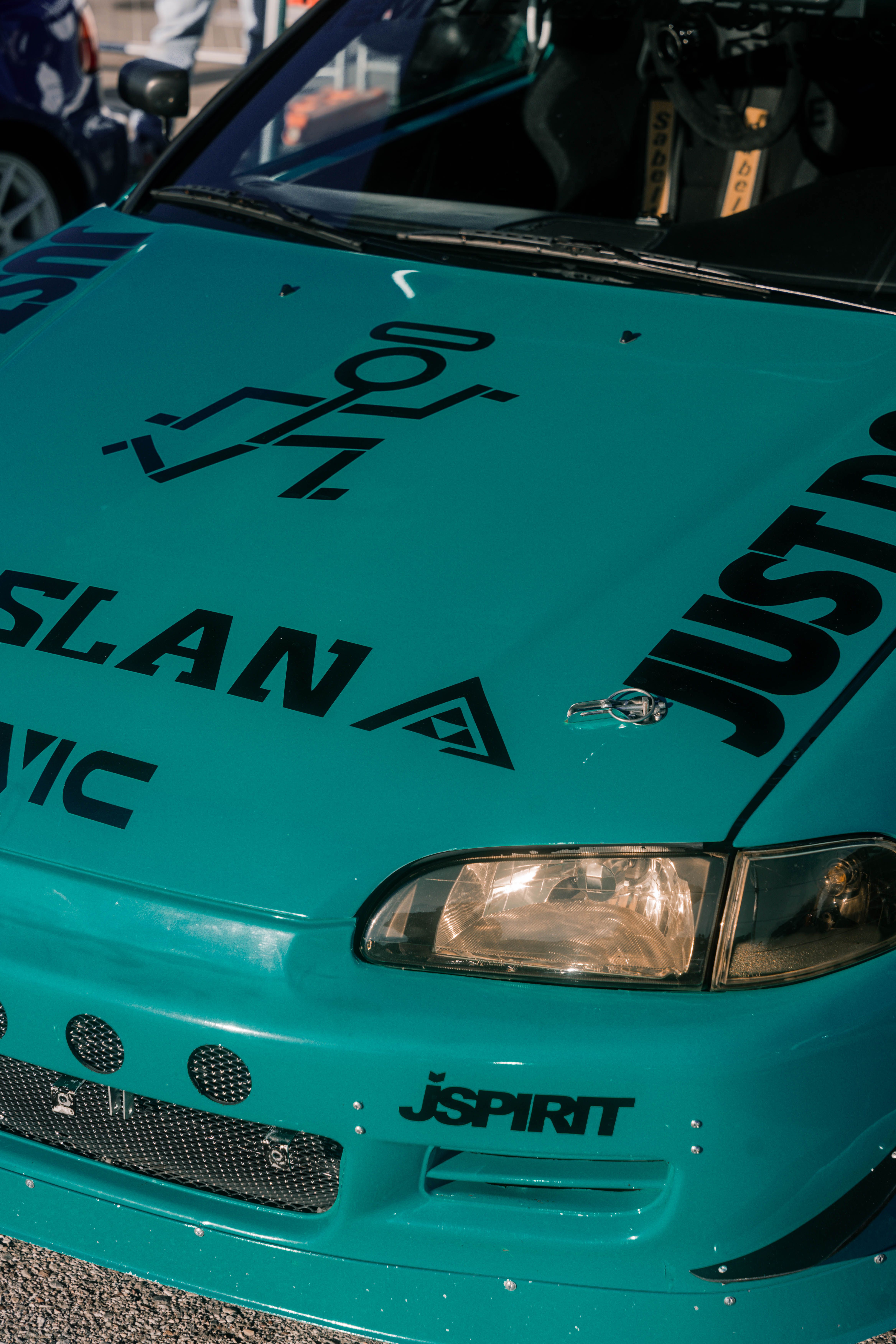 Close-up view of a teal sports car with decals and custom modifications.