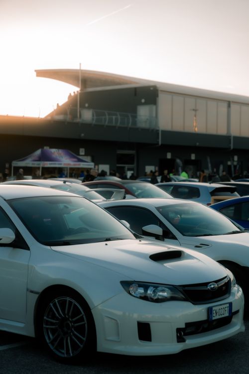 Free White sports car parked in a busy parking lot at a motorsport event in Cremona, Italy during sunset. Stock Photo