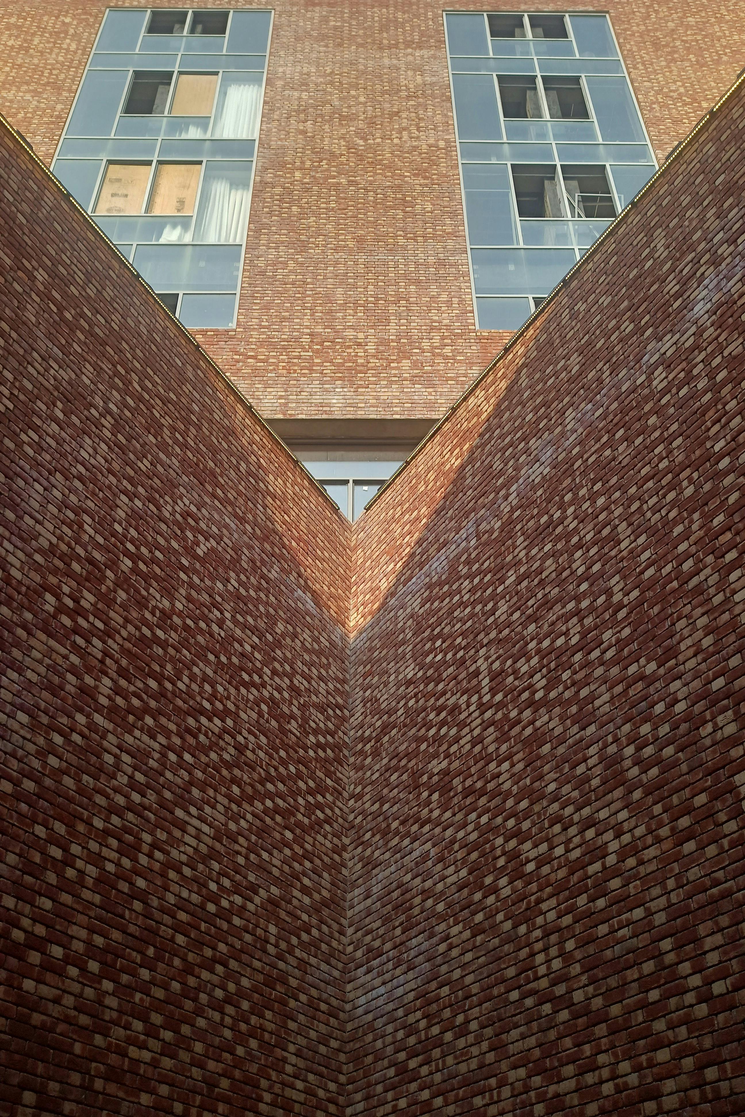 Free A low angle view of a brick building exterior with modern windows capturing architectural symmetry. Stock Photo