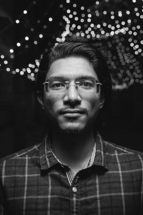 Free Stunning black and white portrait of a man with eyeglasses and short hair under festive lighting. Stock Photo