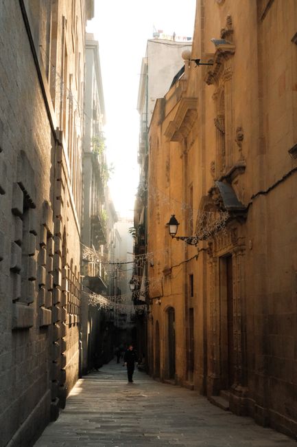 Sunlit alleyway in Barcelona's historic old town with classic architecture.