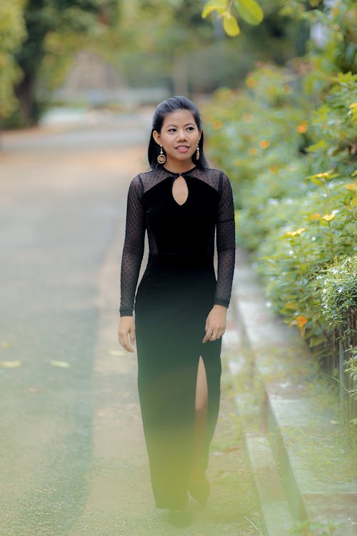 Elegant Woman in a Black Dress Walking in a Park 
