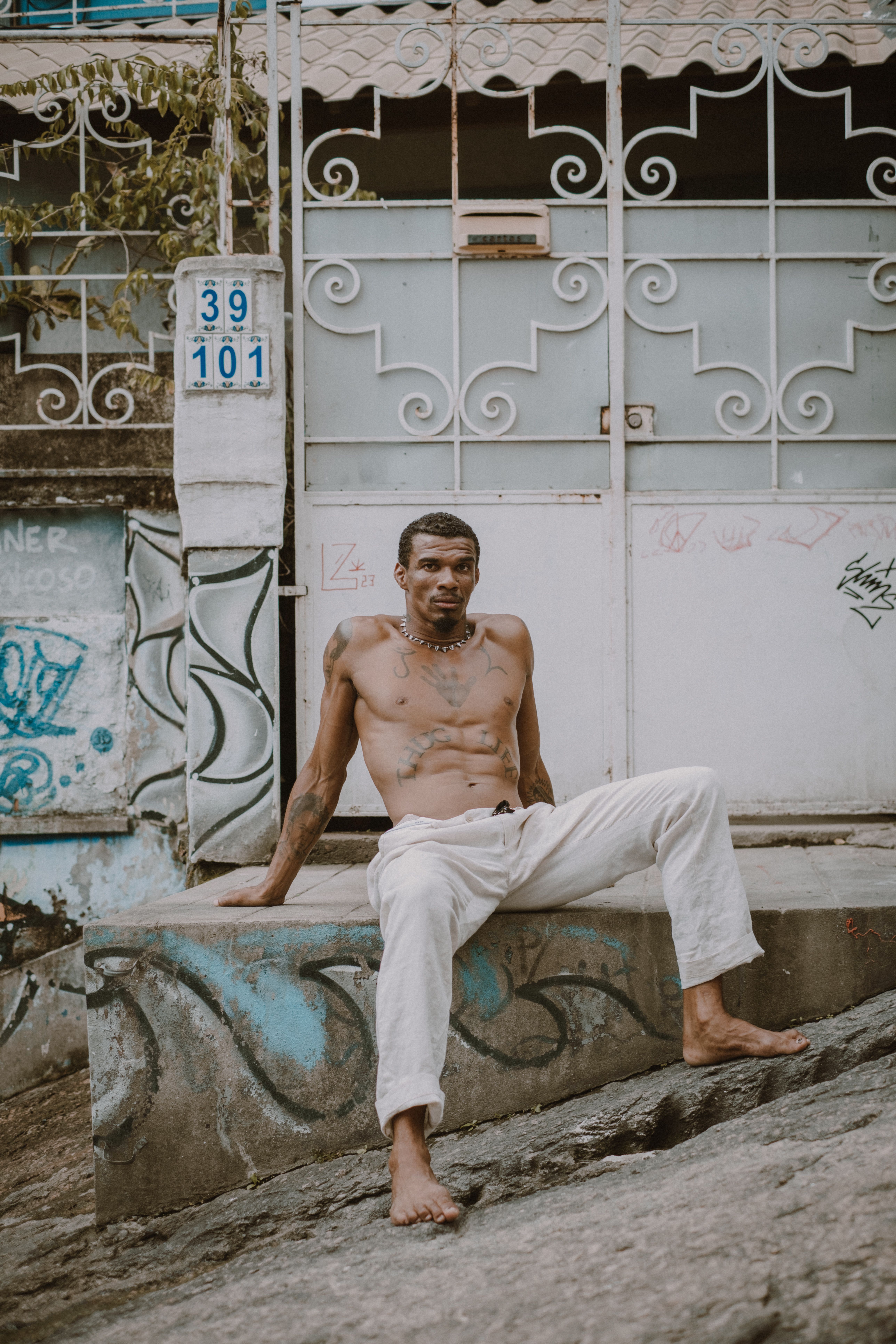 Shirtless tattooed man sitting on urban street in Rio de Janeiro.
