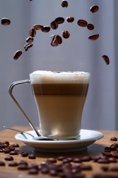 Captivating image of a frothy cappuccino with coffee beans suspended in mid-air.